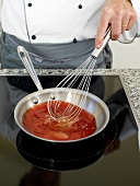 Mixing preparation of gazpacho in saucepan with a whisk