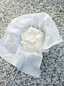 Curd hanging in muslin cloth on strainer