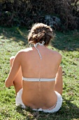 Rear view of woman wearing white bikini sitting on grass