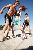 junge Leute am Strand, haben Spaß, spielen Fußball