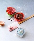 Paper cupcakes, spatula and timer on surface