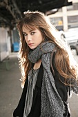 Portrait of skeptical brunette woman with long hair wearing gray scarf