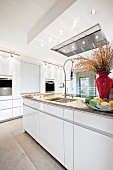 Interiors of kitchen in white with fruit basket and vase on working surface