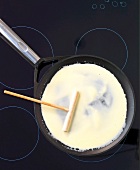 Close-up of pancake batter being spread in pan with wooden slider