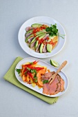 Avocado and tuna salad, pineapple and papaya salad with salmon fillet on plates