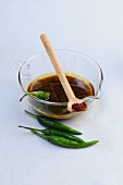 Balsamic vinaigrette in glass bowl with chillies and serving spoon