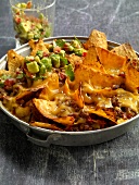 Close-up of nachos with beef and avocado salsa in pan