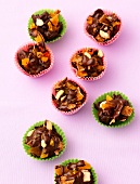 Crunchy nutlets in paper cups on pink background