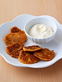 Carrots blinis on plate with bowl of orange sour cream
