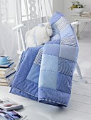 A blue patchwork blanket and a homemade cuddly toy sheep on a rocking chair
