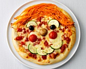 Pizza garnished with vegetables to resemble face