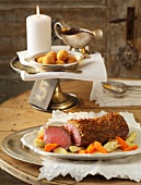 Chateaubriand steak with gingerbread crust, vegetables, sauce and croquettes on table