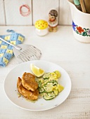 Cucumber salad with chicken nuggets, lime and potato on plate