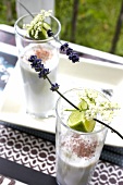 Coconut drink garnished with lavender and lime in glasses