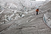 Hiker in front of ice wall in Aletsch Glacier, Marjelesee, Valais, Switzerland