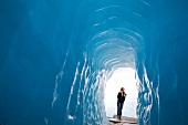 Tourist in ice cave at the Furka Pass in Rhone Glacier, Valais, Switzerland