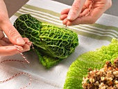 Close-up of hands tying cabbage rolls with kitchen string, step 1