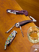 Three pocket corkscrew beside wine glass