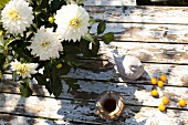 White chrysanthemums and bird figurine on wooden surface, overhead view