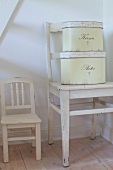 White chair with two antique tin cans on white stool