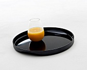 Fruit juice in glass on melamine black tray