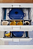 Blue and yellow crockery in open kitchen drawers