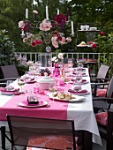 Table setting in pink with crockery and chandelier on terrace