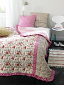 Pink floral pattern bedspread with cushion on bed