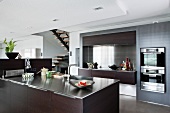 Modern kitchen in wood and stainless steel with stairs in background