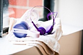 Close-up of purple headphones and water bottle on white napkin on window sill
