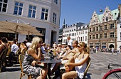 People sitting at table outside Cafe Europa at Amager Square in Copenhagen, Denmark