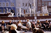 People relaxing in front of ship at Nyhavn harbour, Copenhagen, Denmark