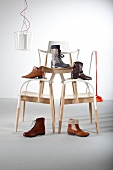 Various boots on stack of chairs against white wall