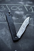 Handmade folding knife on blackboard