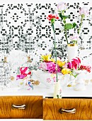 Altes Porzellangeschirr als Blumenvase auf Schubladenschrank vor Blumentapete