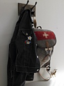Jacket and backpack with sewn emblem alpine motifs hanging on wall