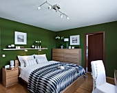 Schlafzimmer mit Doppelbett, Wände in Grün, helles Holz