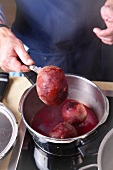 Boiled beetroot being removed from pressure cooker with knife