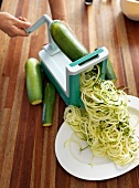 Close-up of zucchini being sliced in vegetable slicer