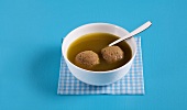 Bowl of liver dumpling soup on blue background
