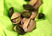 Pistachio in broken shell on green background