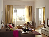 View of living room with brown sofa, glass table, armchair and floor lamp