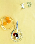 Orange blossom water bottle and plates of ginger syrup and grenadine syrup, overhead view
