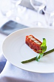 Terrine of confit tomatoes with shrimp and garnished with basil and tarragon pesto