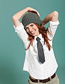 Cheerful business woman wearing white cotton blouse, tie and knitted hat, laughing
