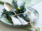 A napkin and a pine sprig on a plate decorated for Christmas
