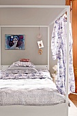 View of modern four poster bed with curtain and modern abstract painting and wall hanging