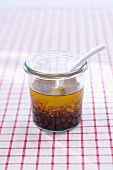 Vinaigrette in glass jar with spoon on checked tablecloth