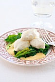 Pike dumplings with spinach and saffron sabayon on plate