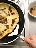 Picking pancake with raisins on spatula while preparing, step 2